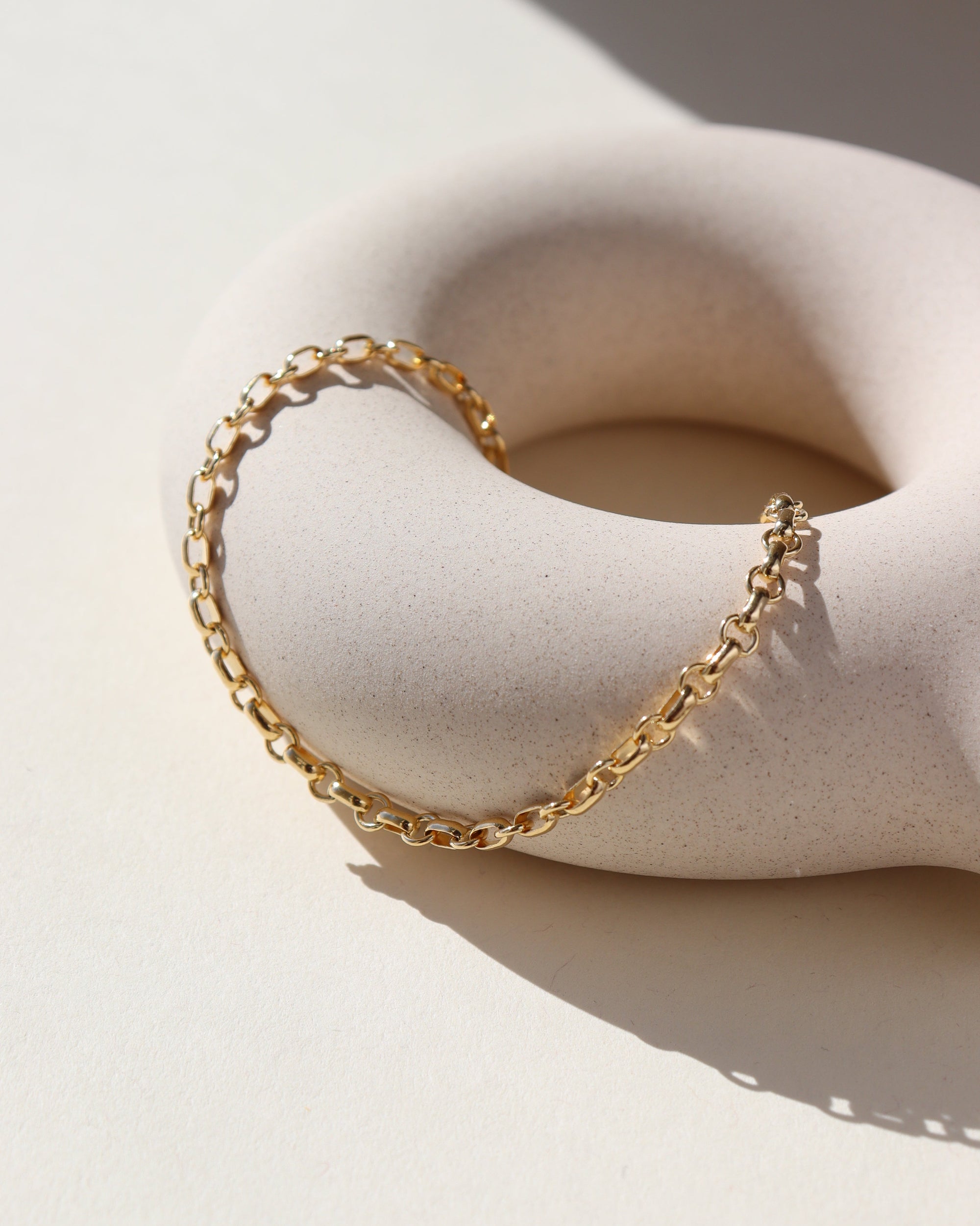 Roen Bracelet laid on a tan plate in the sunlight