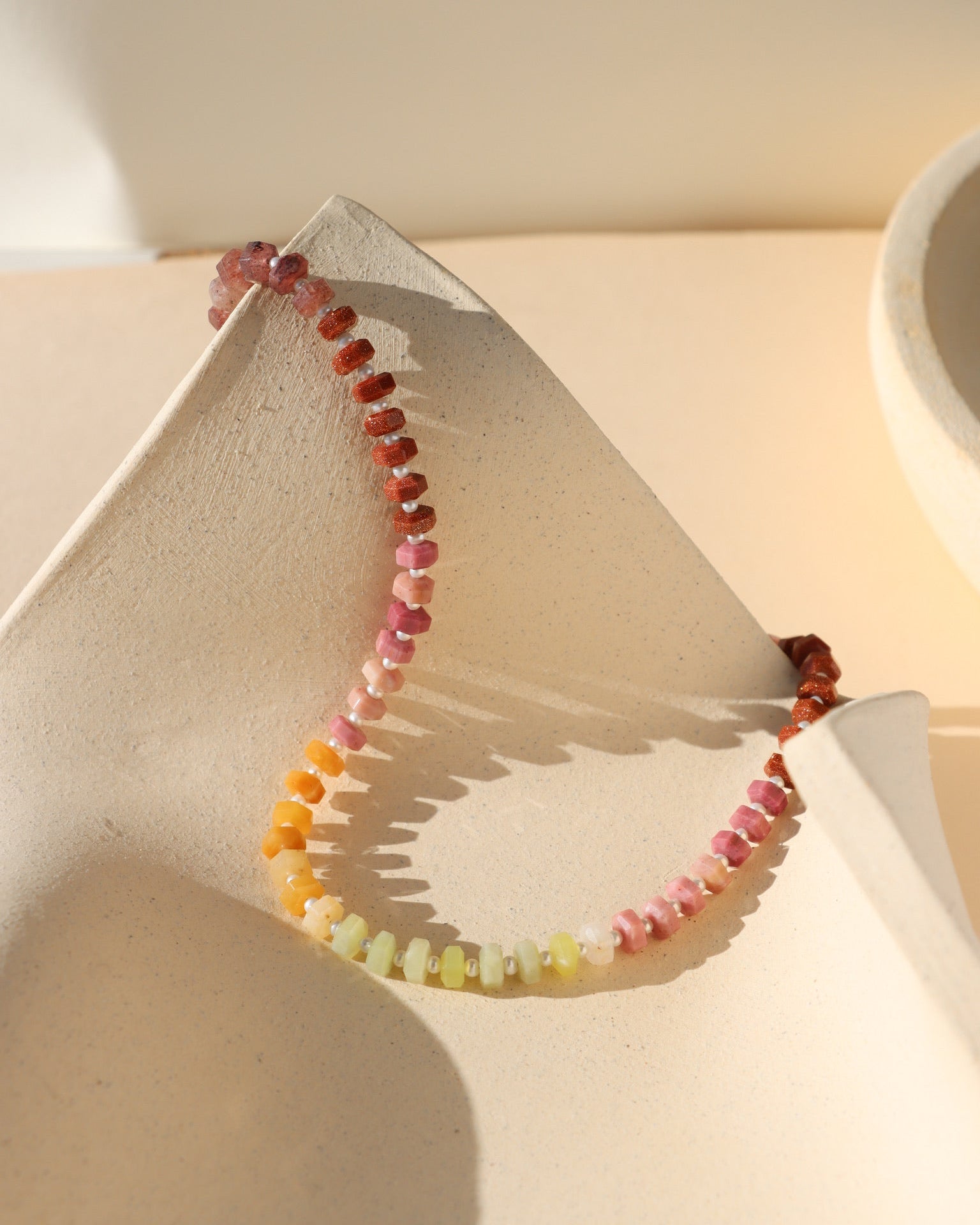 multi colored stone beads with pearls necklace displayed in the sunlight