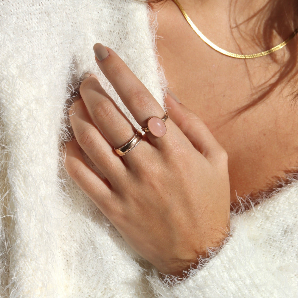 Model is wearing our rose quartz entwined ring in 14k gold fill, this ring features a rose quartz stone on a textured thick band. This band has a "entwined" textured look. The model is also wearing our Lainey ring, this is a thick gold band with ripples on the edges and a hammered band. 