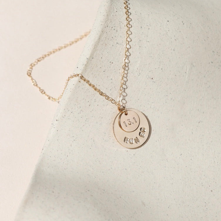 14k gold fill hand stamped round discs charm on a delicate chain necklace on a light surface