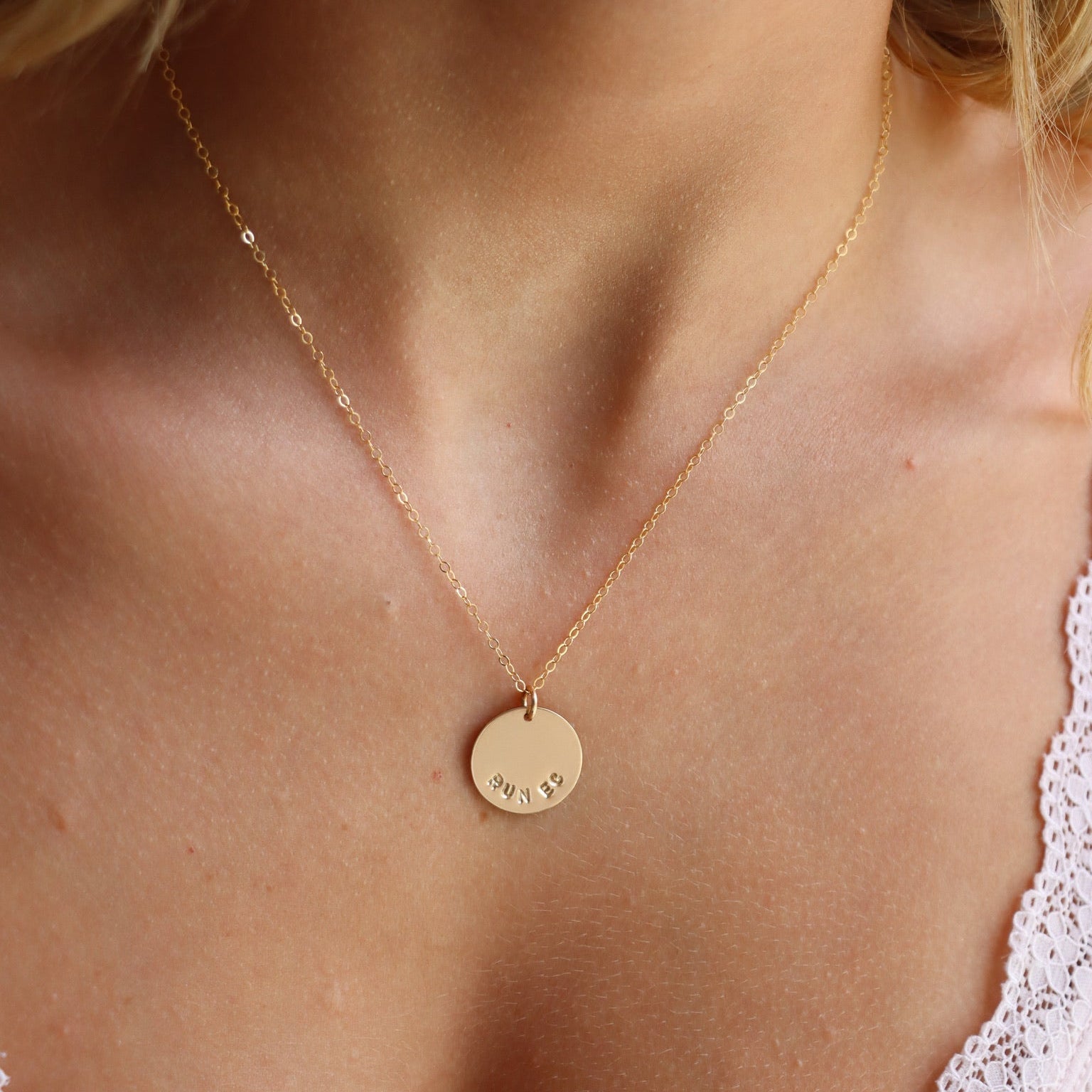 model wearing 14k gold fill delicate chain necklace with hand stamped round disc that says "run ec"