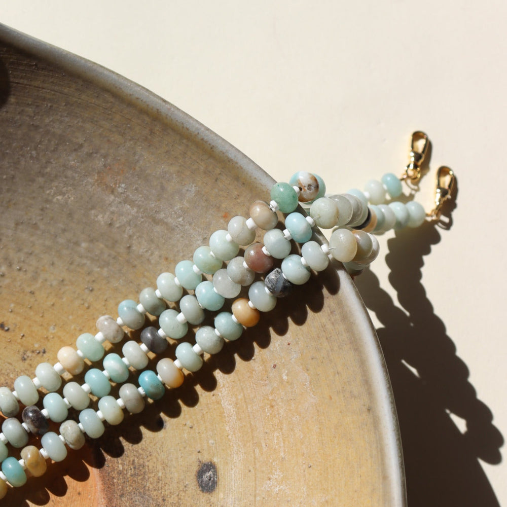 A fully beaded 14k gold fill anklet filled with amazonite gemstones and shell spacer beads. The anklet is displayed on a dish. 