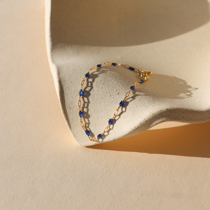 14k gold fill chain with transparent sapphire enamel as a bracelet on a light dish