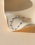 sterling silver chain alternating with transparent sapphire creating a dainty bracelet on a light dish