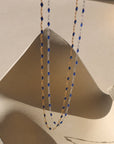 14k gold fill chain with sapphire gemstones paired with sterling silver chain with sapphire gemstones hanging with a light background