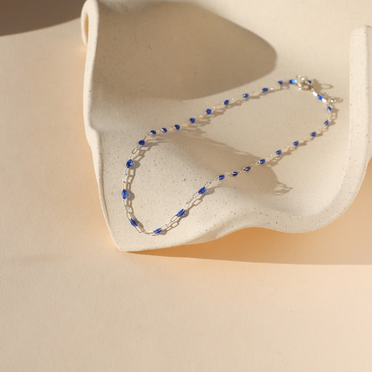 sterling silver chain bracelet with sapphire gemstones on a light dish in the sunlight