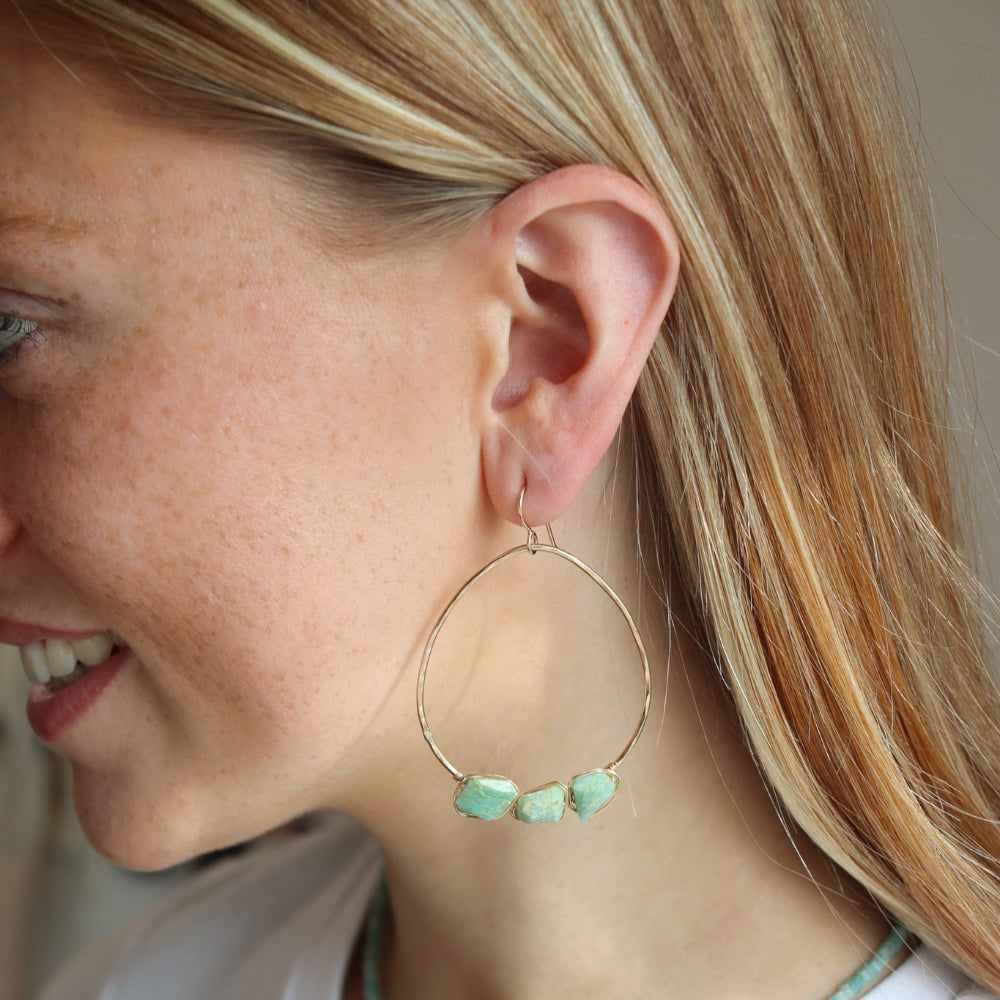 A model wearing a 1.75 wide 14k gold fill wire hoop with three amazonite gemstones wire wrapped at the bottom of each earring. 