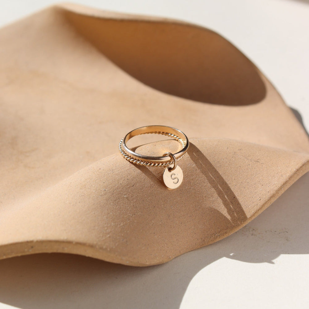 A smooth band stacked with a spiral 14k gold fill band, with a small &quot;S&quot; stamped disc attached to both rings. 