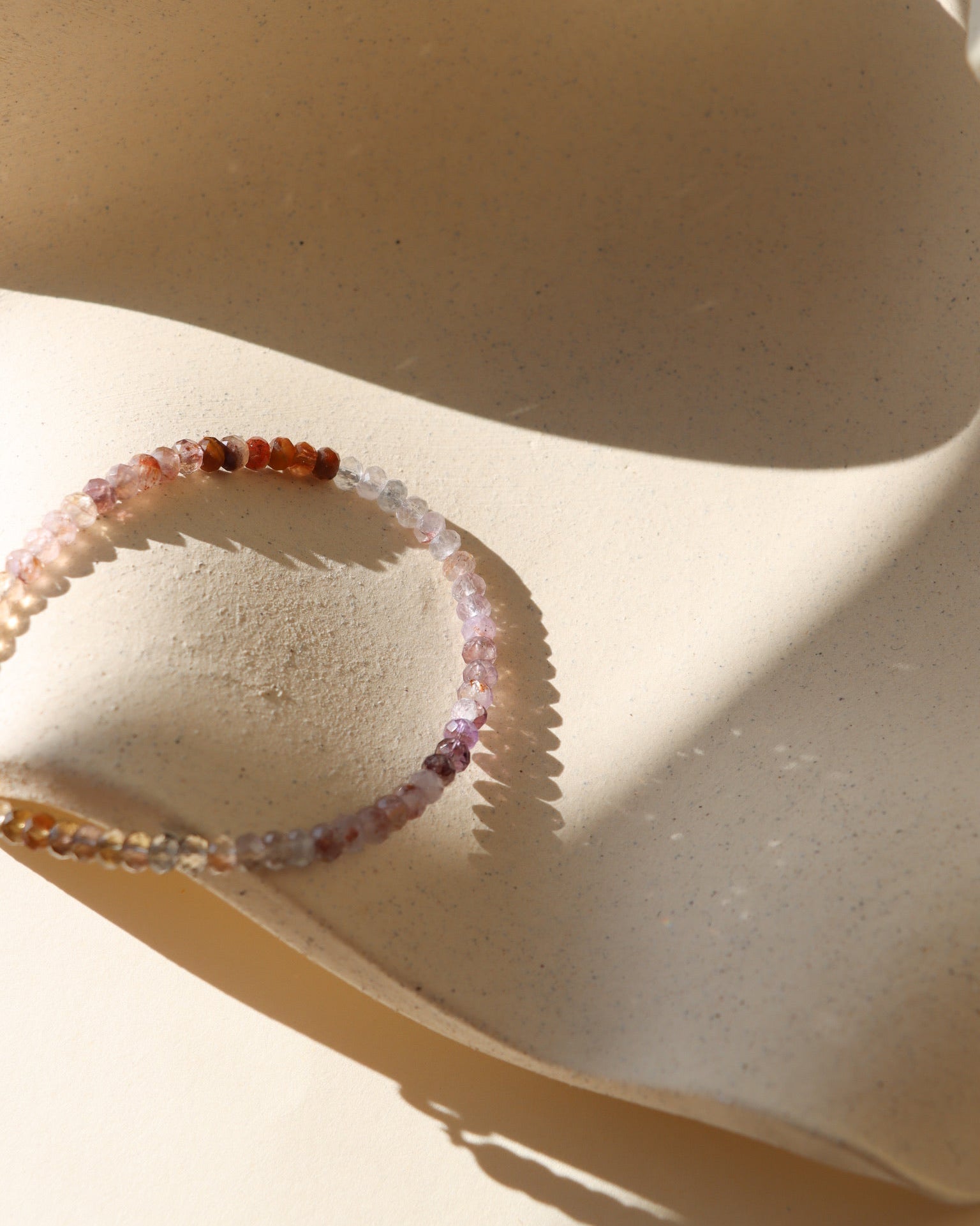 Beaded bracelet on a textured beige surface with soft shadows