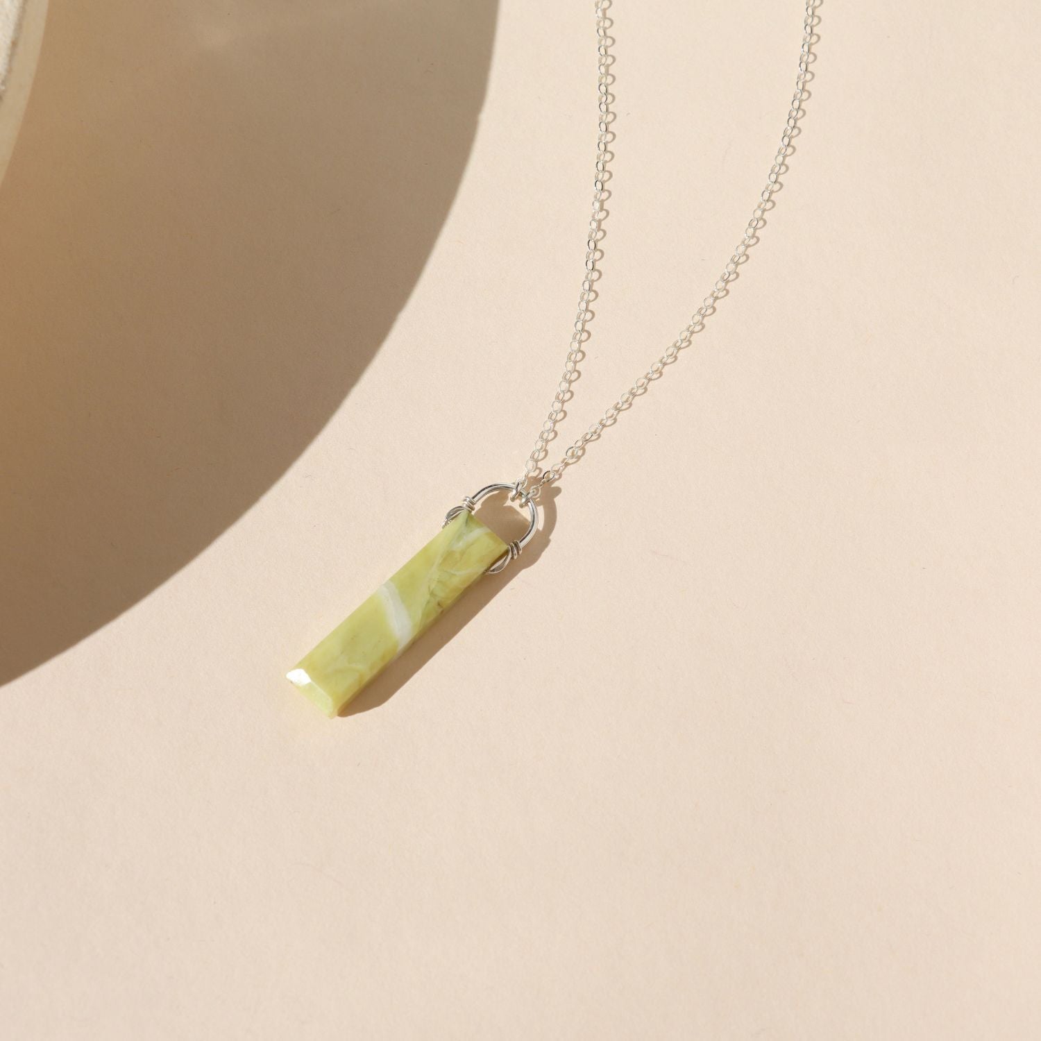 sterling silver chain necklace with rectangle serpentine pendant on a light dish