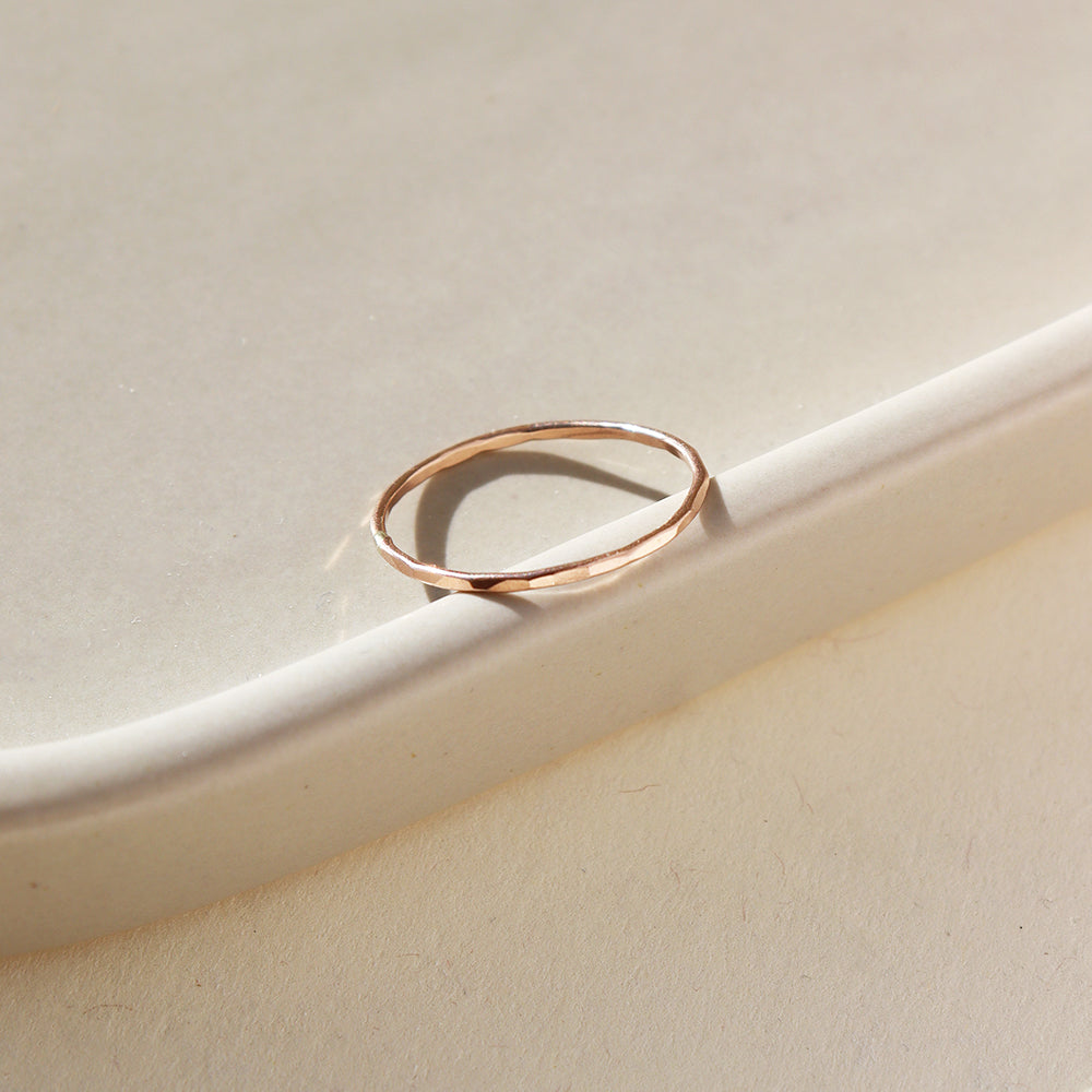 14k gold fill skinny ring laid on a white dish