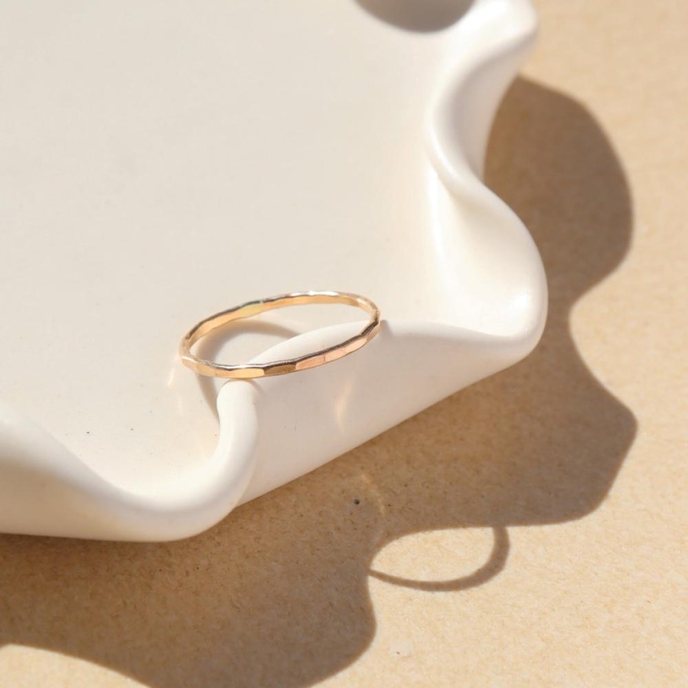 14k gold fill skinny ring laid on wavy plate in sunlight