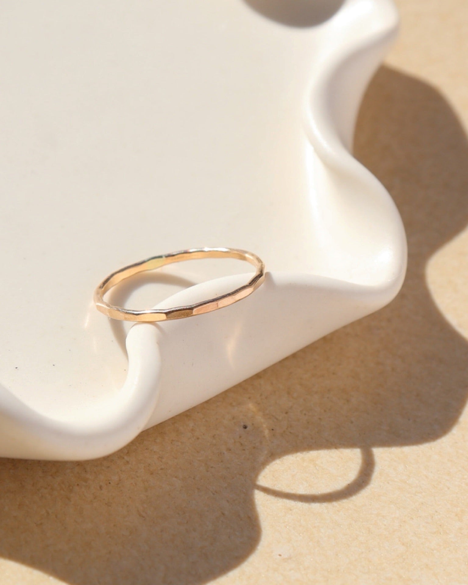 14k gold fill skinny ring laid on wavy plate in sunlight