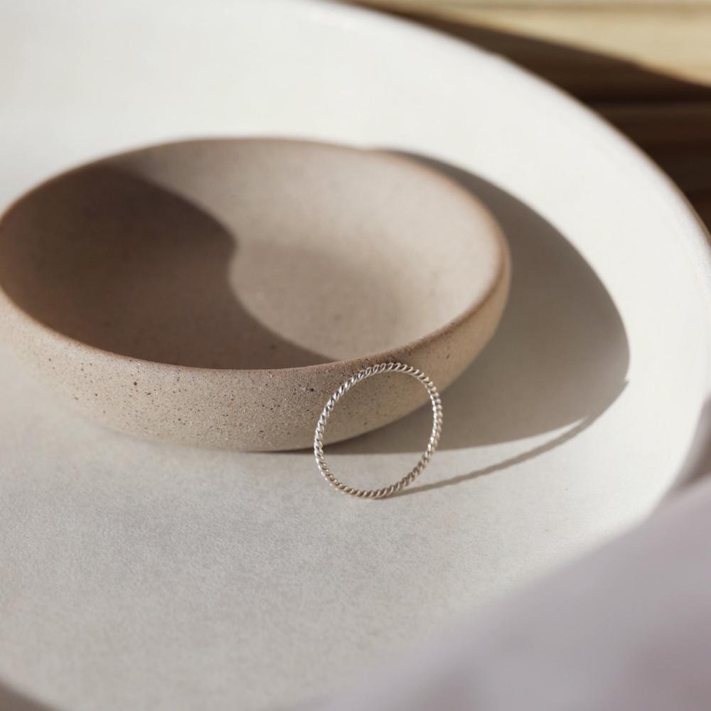 925 Sterling silver spiral ring laid against a gray plate in the sunlight.