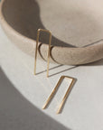 14k gold fill Staple earrings placed in the sunlight on a gray plate. A minimal earring that's perfect for everyday. Wear them in your second ear holes or let them be the main adornment for your ear lobes! Either way, these earrings will become one of your daily staples (pun, intended!).