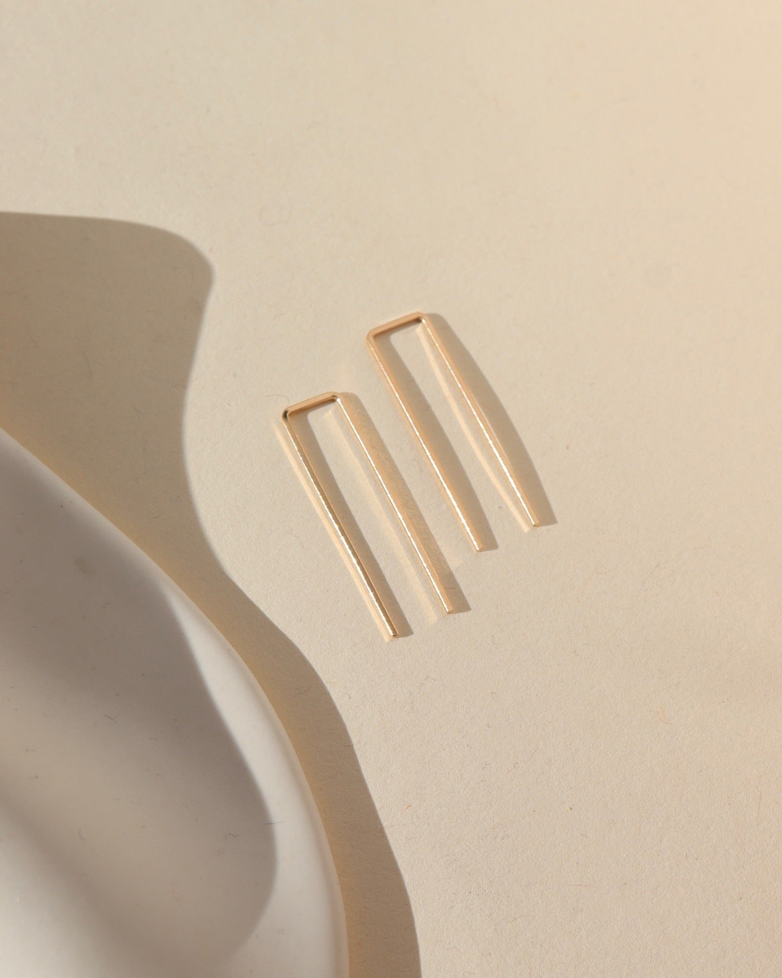 14k gold fill staple earrings laid in the sunlight