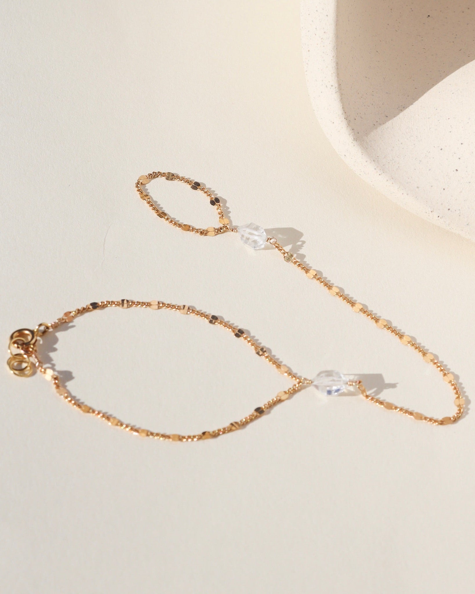 Gold sunburst hand chain featuring delicate textured links and a raw Herkimer diamond accent.