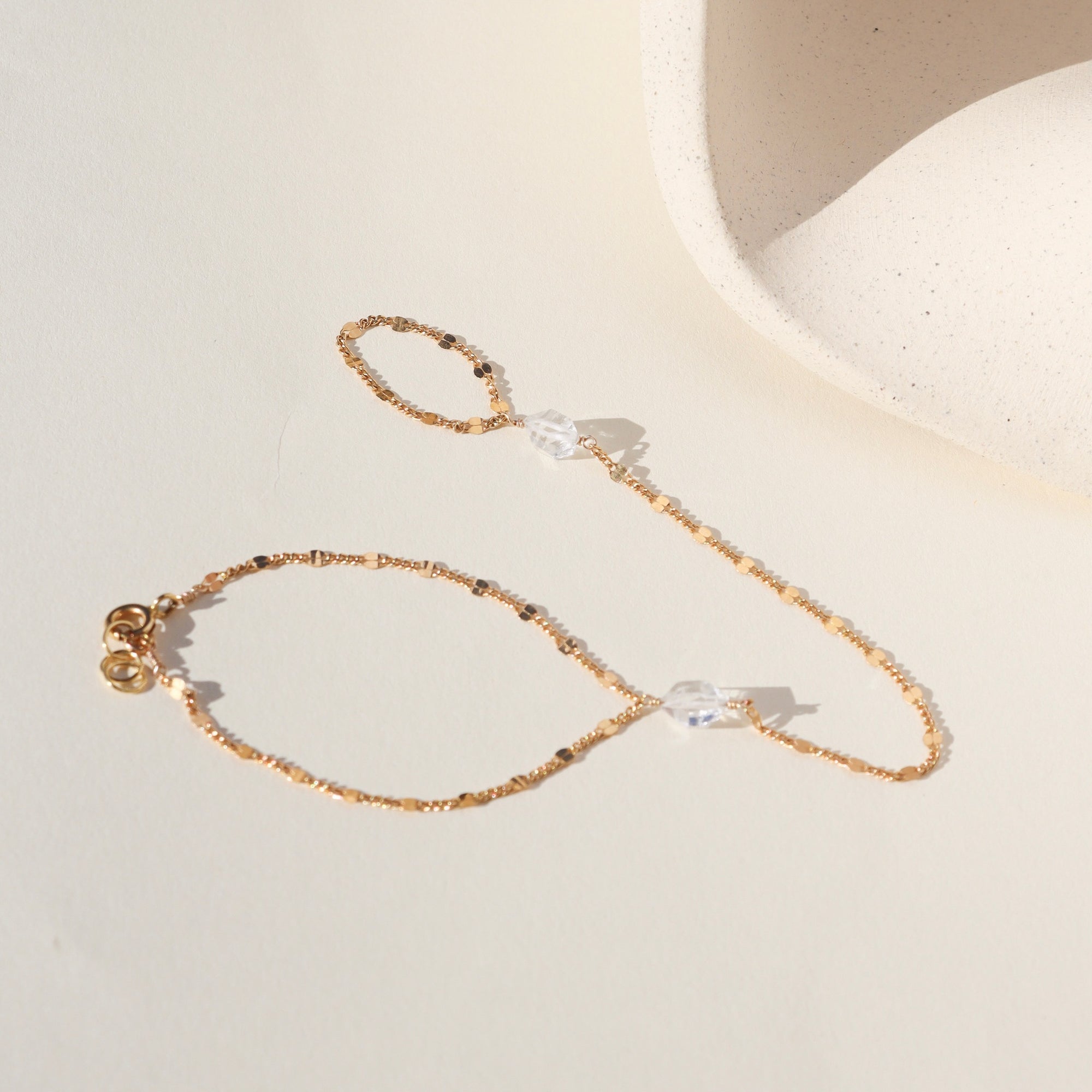 Gold sunburst hand chain featuring delicate textured links and a raw Herkimer diamond accent.