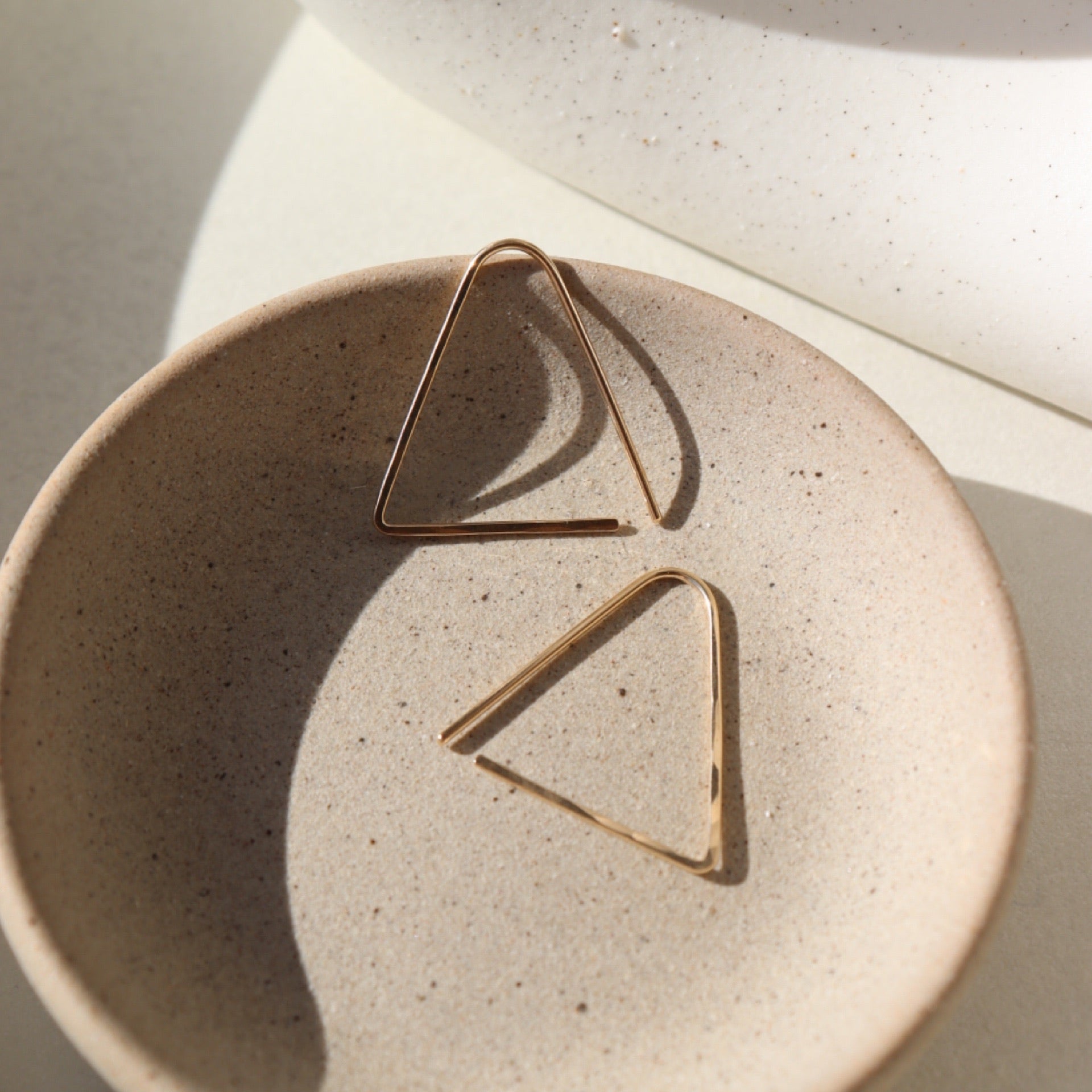 14k gold fill hammered triangle earrings on a light dish