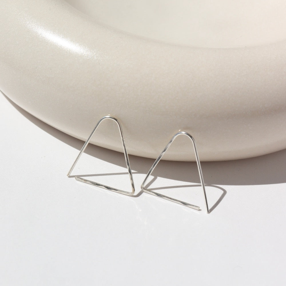 sterling silver hammered triangle earrings on a light dish