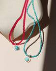 photo showing a round turquoise pendant on two different beaded necklaces