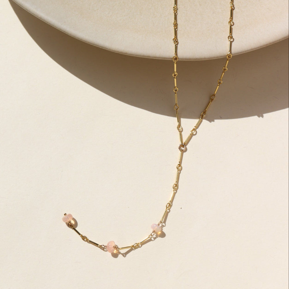 A 14k gold fill bar and link chain with three peach opal gemstones in a lariat style necklace. 