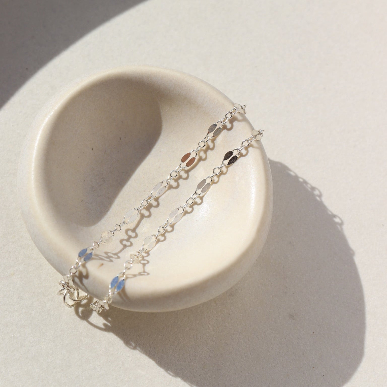 sterling silver double bar chain bracelet on a light dish