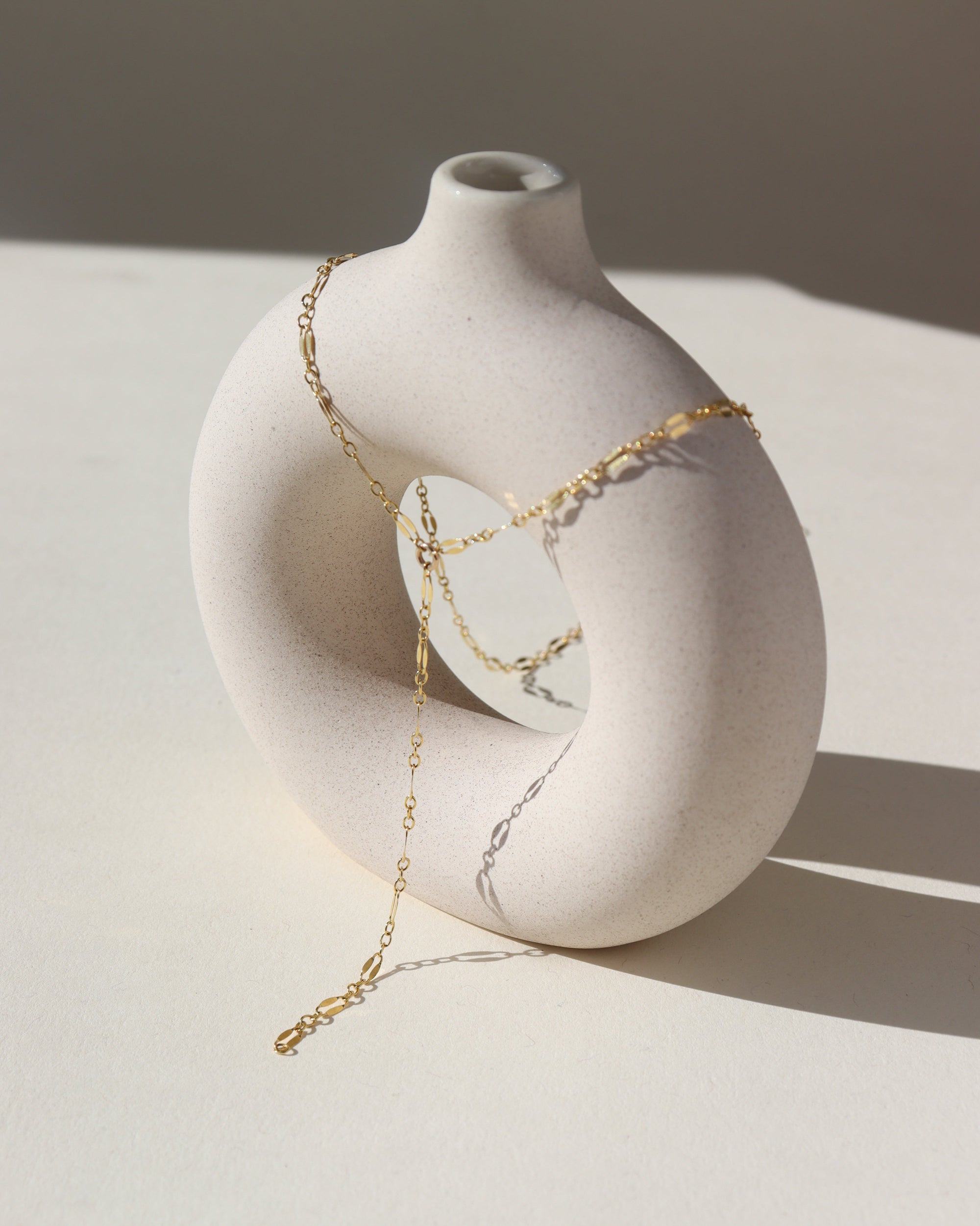 14k gold fill lariat chain, photographed on a cream colored ceramic dish