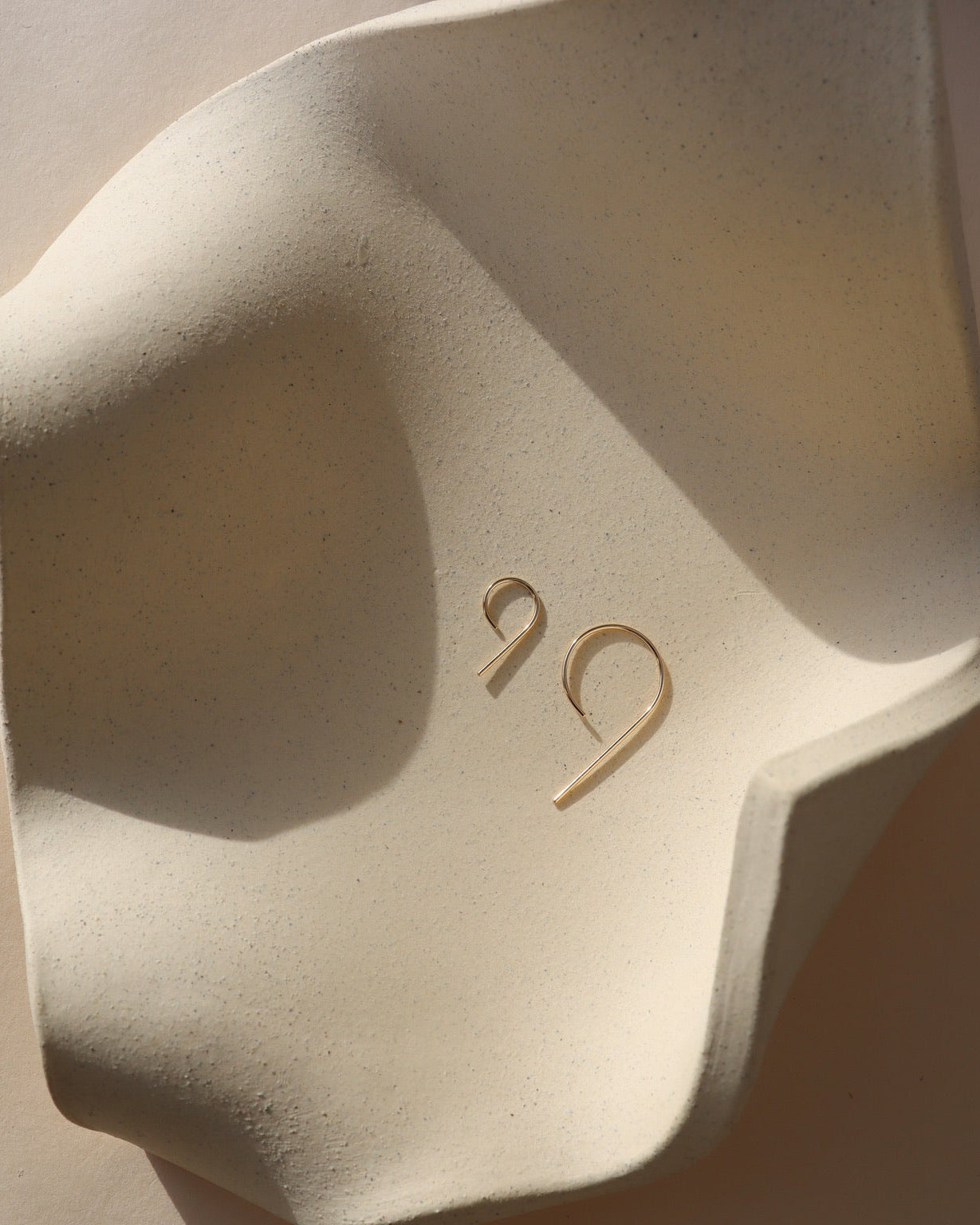 14k gold fill 9 shaped earrings in 2 sizes on a light dish