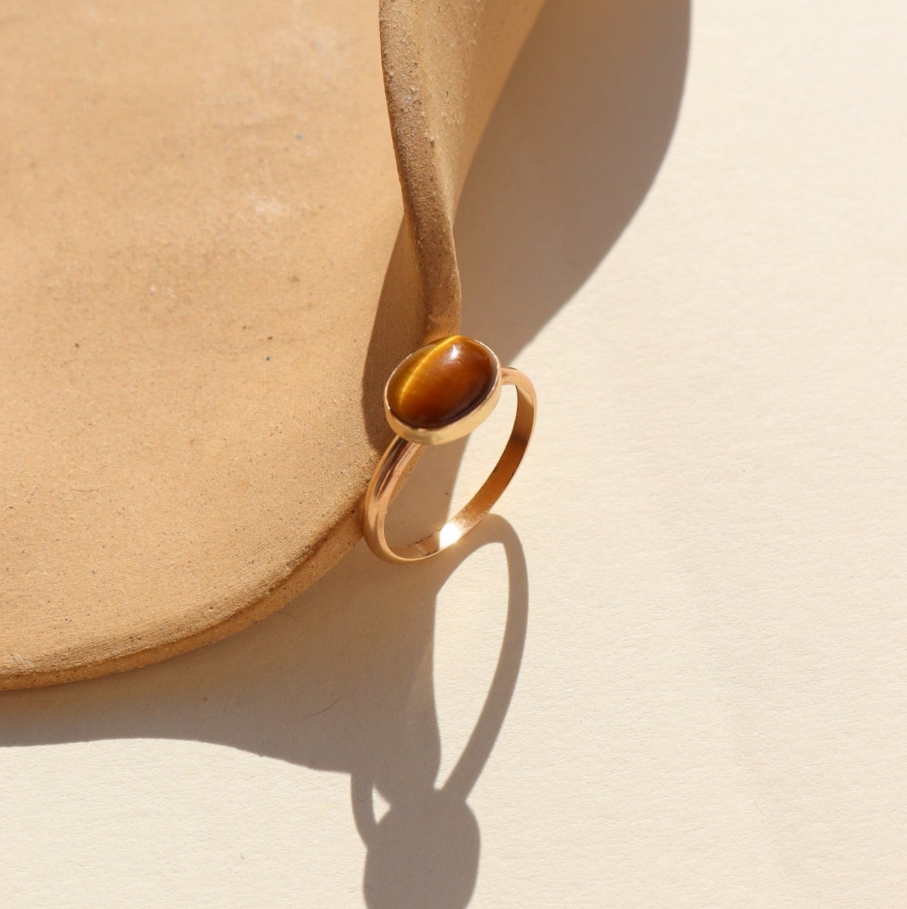 An amber-colored Tiger Eye gemstone on a horizontal bezel on a 14k gold fill band