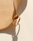 An amber-colored Tiger Eye gemstone on a horizontal bezel on a 14k gold fill band