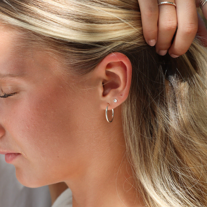 model wearing sterling silver tiny domed circle studs with sterling silver hoops
