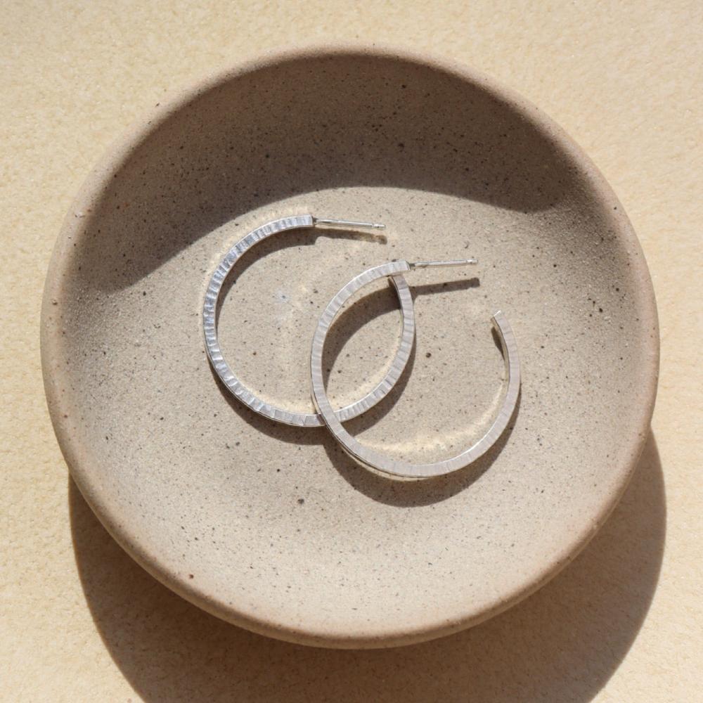 petite maeve hoops in 925 sterling silver by token jewelry, a medium-sized hoop with a post, featuring a textured edge