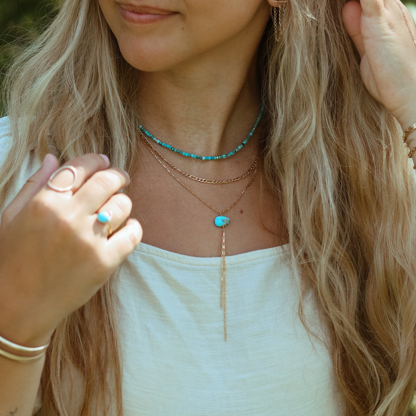 Turquoise Gemstone beaded necklace layered with a 14k gold fill chain necklace and a gold filled lariat with a turquoise stone anchored in the middle on a model.