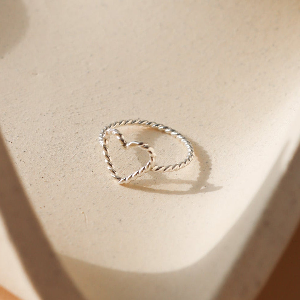 sterling silver spiral wire heart shaped ring on a light dish