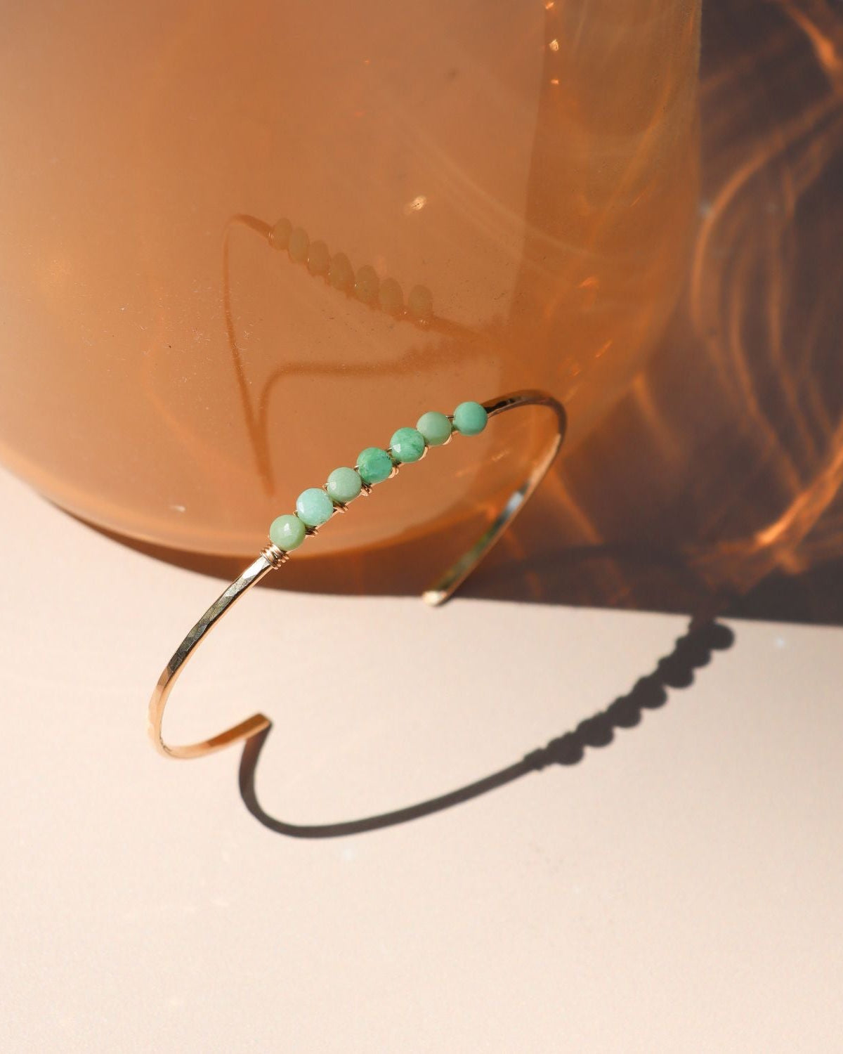  14k gold fill jewelry including a cuff with wire wrapped chrysoprase stones in the sunlight