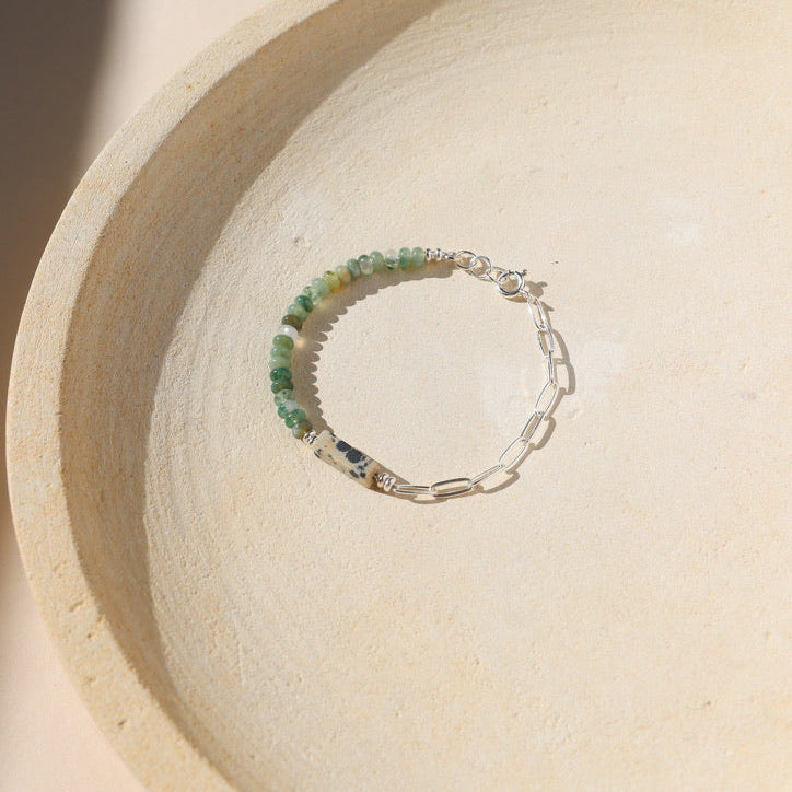 sterling silver paperclip chain with moss agate and dalmatian jasper beads on a light dish