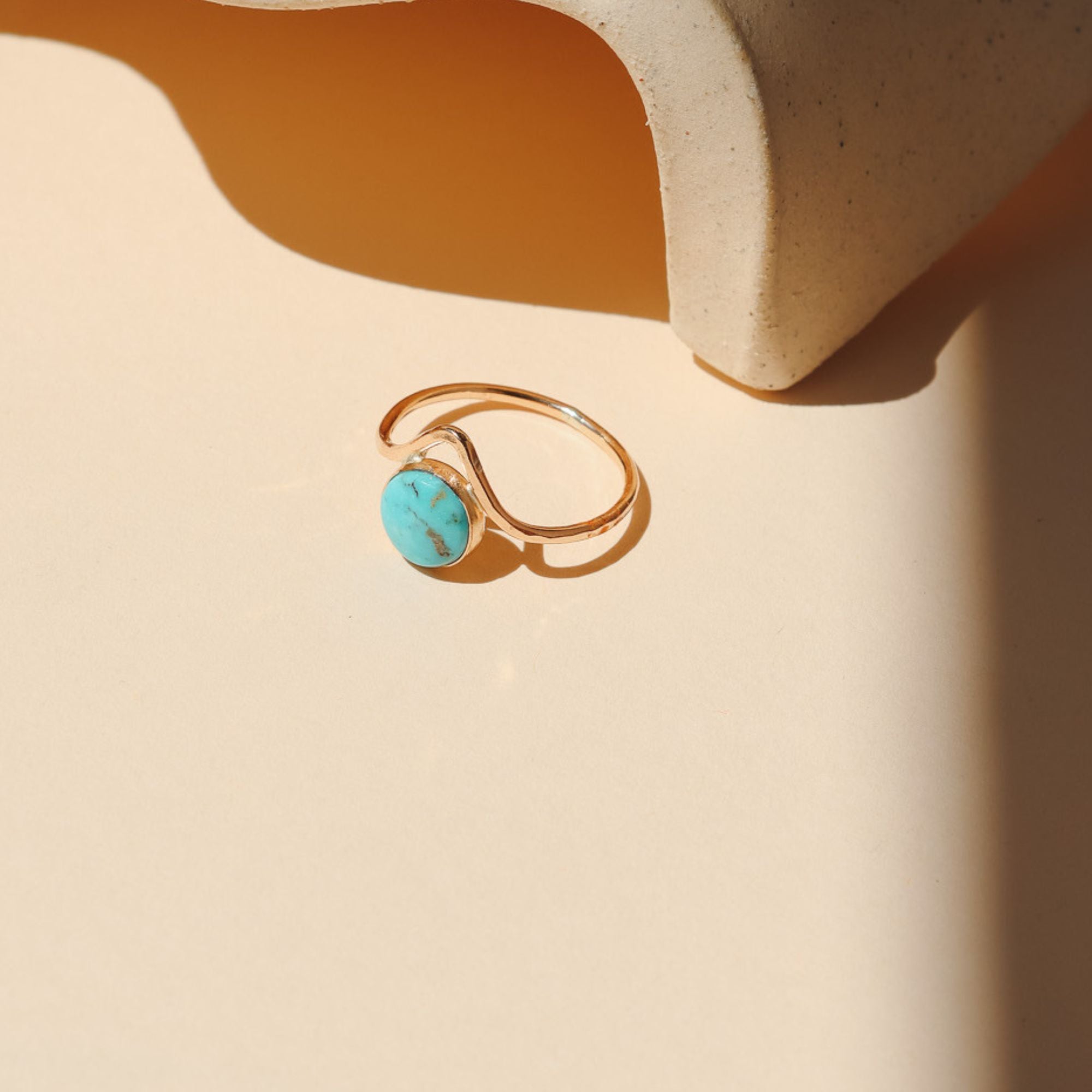 14k gold fill ring with point and round turquoise stone on a light dish
