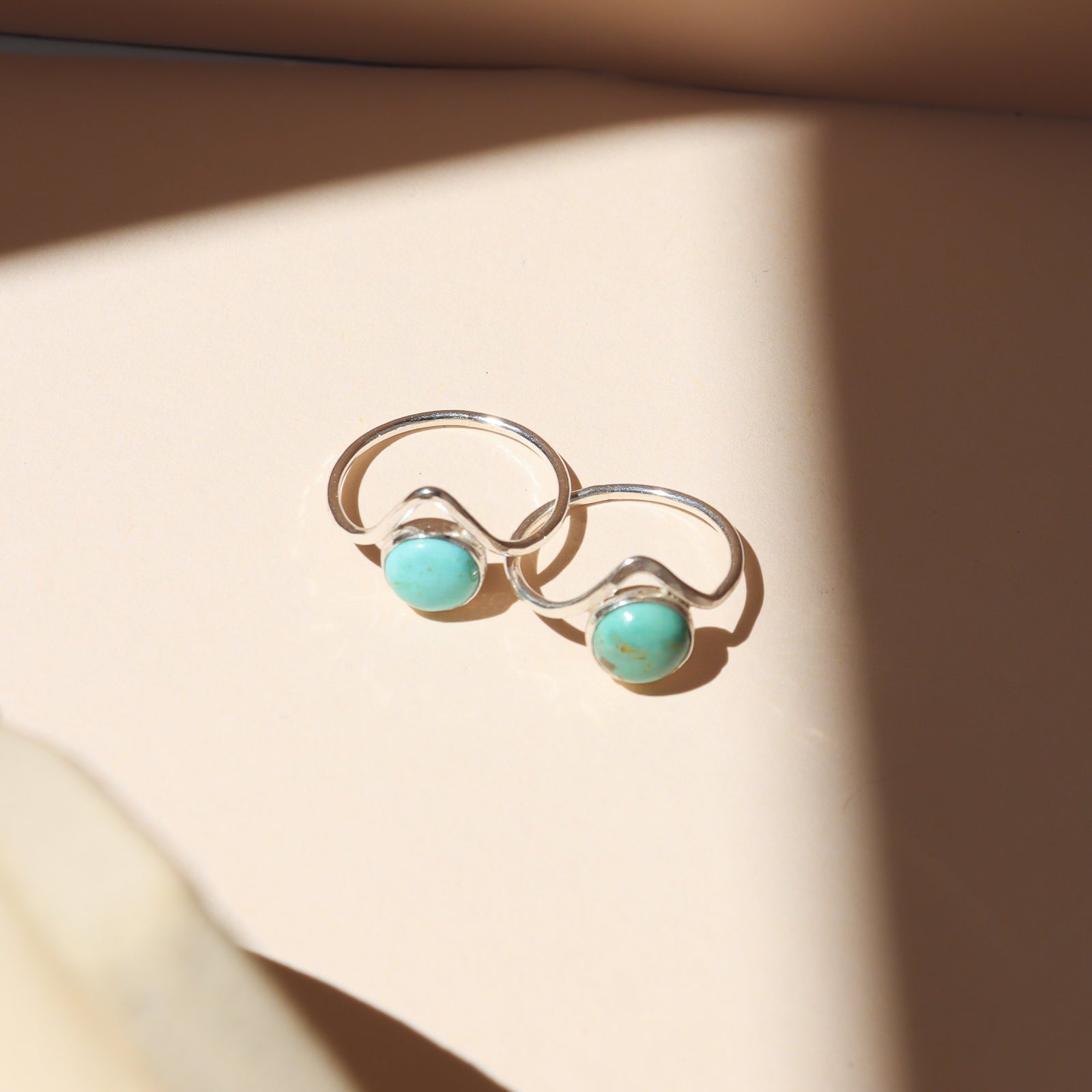 sterling silver rings with point and round turquoise stone on a light dish