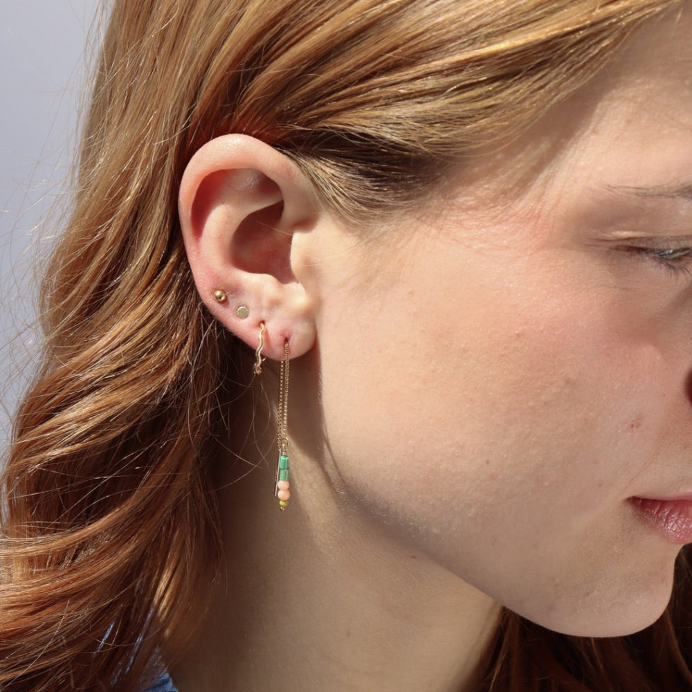 Model wearing 14k gold fill threaders with two coral beads, two turquoise tubes, and one serpentine bead jumped to the bottom of each threaders