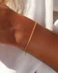 Westly bracelet by Token Jewelry photographed on a model. The bracelet is a delicate 14k gold wheat-inspired chain.