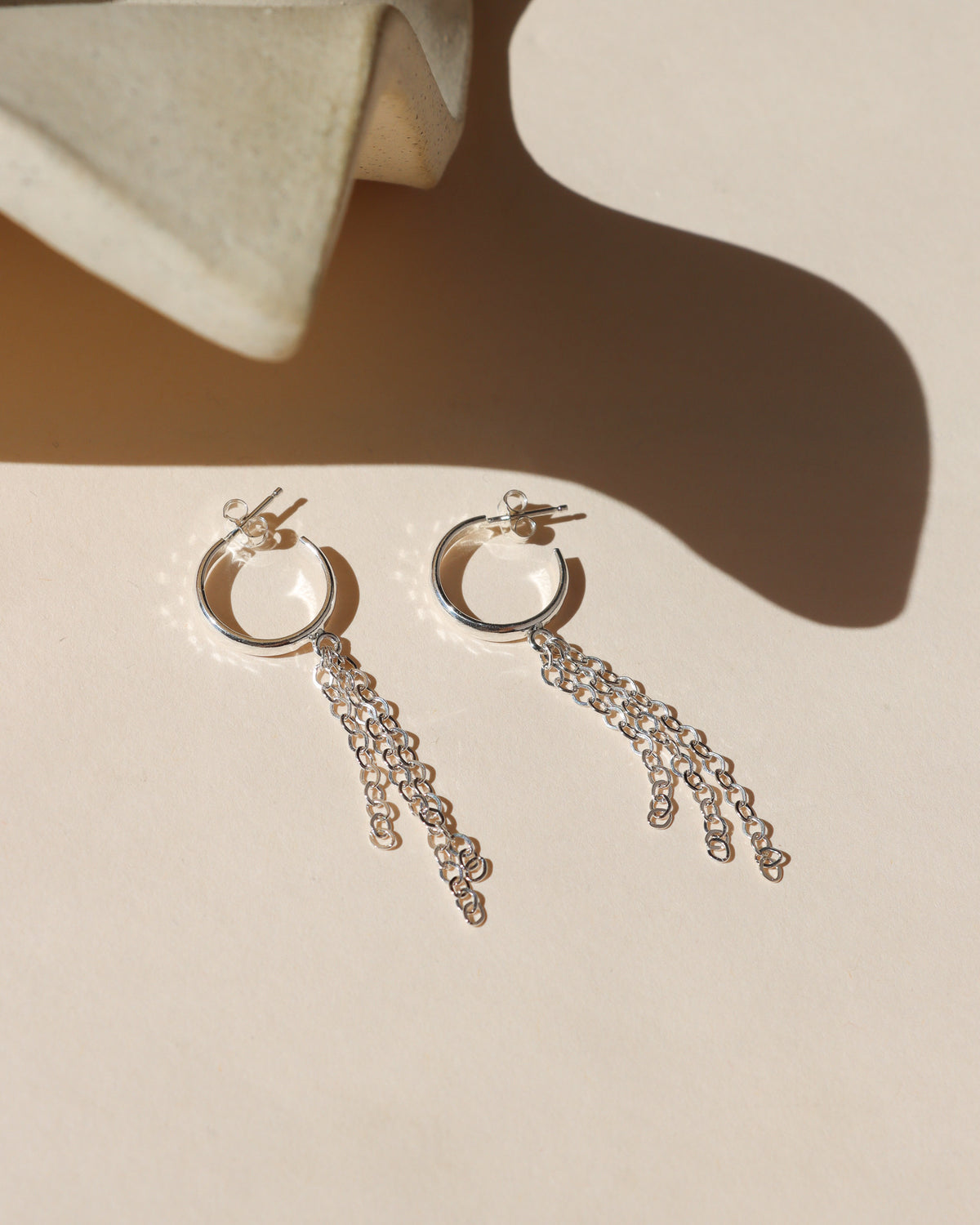Delicate sterling silver hoop earrings with cascading chain fringe, designed to catch the light with every movement.