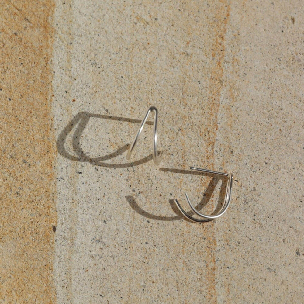 sterling silver wishbone shaped studs on a light surface