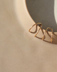 14k gold fill wishbone studs laid on a tan plate in the sunlight.