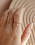 hand wearing a 14k gold fill spiral band with a small heart charm, and a hammered Infinity Ring with two bands