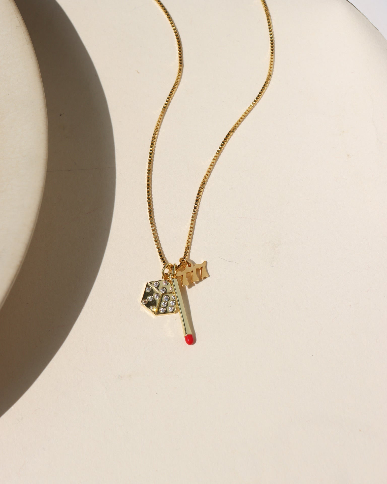 14k gold fill chain necklace with a dice charm, matchstick charm, and a 777 charm 
