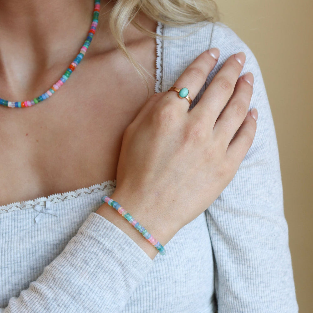 Model wearing a vibrant colorful bracelet filled with a mix of different opal gemstones. This bracelet has a 14k gold fill standard clasp a 0.5" extender. 