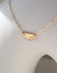 14k gold fill necklace Laid on a white pot. This necklace features a half circle hammered in the middle each side connected by the cosset chain.