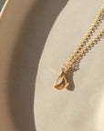 14k gold fill Wishbone Necklace laid on a tan plate in the sunlight.