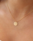 Model Wearing Mini Coin Necklace. This Necklace features a coin disc hammered on the outside of the circle. it slides around on the coin necklace chain.